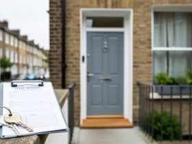 Key and clipboard beside a UK flat entrance and window, suggesting buying considerations for a short-lease apartment.